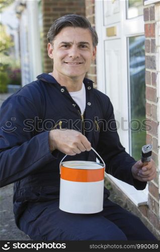 Man Holding Brush And Tin Painting Outside Of House