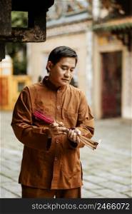 man holding bundle incense temple