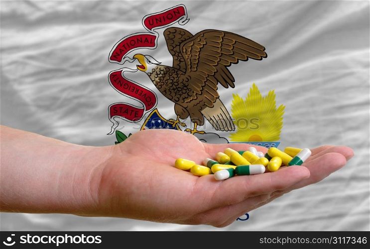 man holding capsules in front of complete wavy american state flag of illinois symbolizing health, medicine, cure, vitamines and healthy life