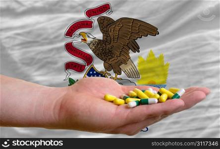 man holding capsules in front of complete wavy american state flag of illinois symbolizing health, medicine, cure, vitamines and healthy life