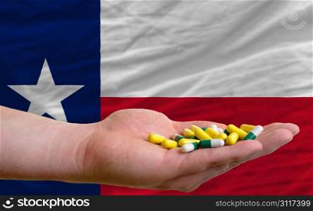 man holding capsules in front of complete wavy american state flag of texas symbolizing health, medicine, cure, vitamines and healthy life