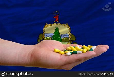 man holding capsules in front of complete wavy american state flag of vermont symbolizing health, medicine, cure, vitamines and healthy life