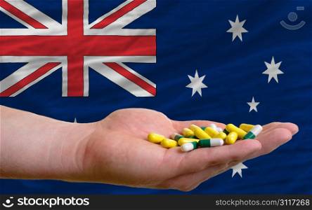 man holding capsules in front of complete wavy national flag of australia symbolizing health, medicine, cure, vitamines and healthy life