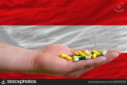 man holding capsules in front of complete wavy national flag of austria symbolizing health, medicine, cure, vitamines and healthy life