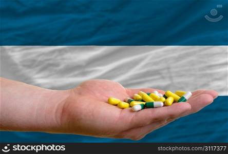 man holding capsules in front of complete wavy national flag of el salvador symbolizing health, medicine, cure, vitamines and healthy life
