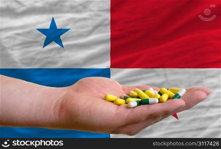 man holding capsules in front of complete wavy national flag of panama symbolizing health, medicine, cure, vitamines and healthy life