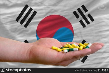 man holding capsules in front of complete wavy national flag of south korea symbolizing health, medicine, cure, vitamines and healthy life