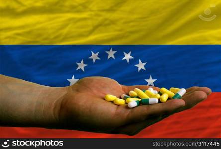 man holding capsules in front of complete wavy national flag of venezuela symbolizing health, medicine, cure, vitamines and healthy life