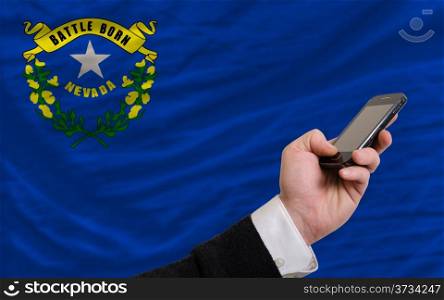 man holding cell phone in front flag of us state of nevada symbolizing mobile communication and telecommunication