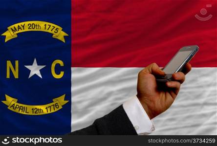 man holding cell phone in front flag of us state of north carolina symbolizing mobile communication and telecommunication