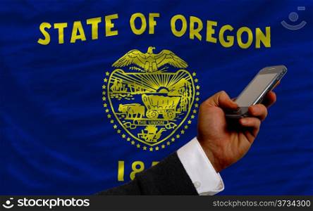 man holding cell phone in front flag of us state of oregon symbolizing mobile communication and telecommunication