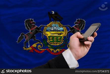 man holding cell phone in front flag of us state of pennsylvania symbolizing mobile communication and telecommunication
