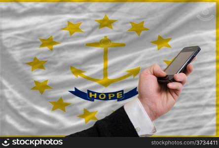 man holding cell phone in front flag of us state of rhode island symbolizing mobile communication and telecommunication