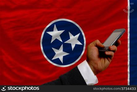 man holding cell phone in front flag of us state of tennessee symbolizing mobile communication and telecommunication