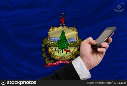 man holding cell phone in front flag of us state of vermont symbolizing mobile communication and telecommunication