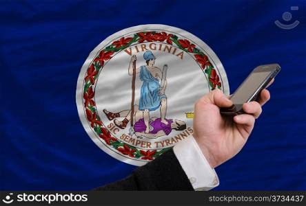 man holding cell phone in front flag of us state of virginia symbolizing mobile communication and telecommunication