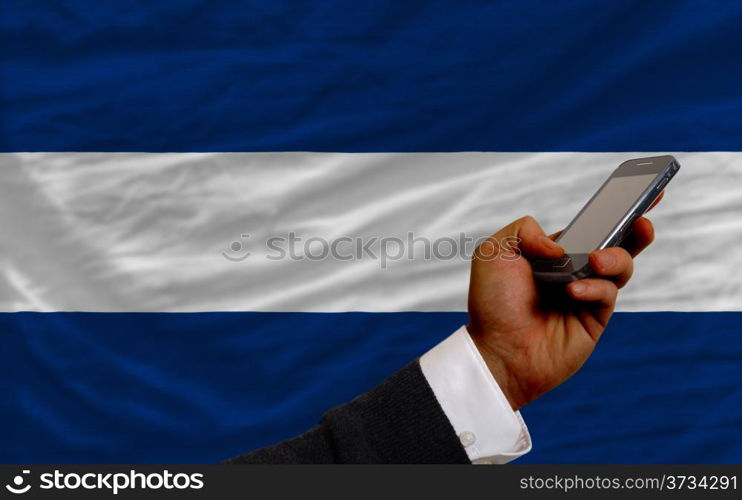 man holding cell phone in front national flag of nicaragua symbolizing mobile communication and telecommunication