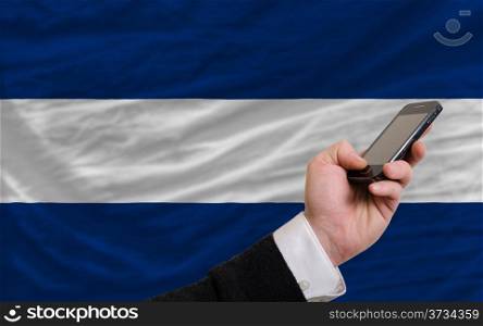 man holding cell phone in front national flag of nicaragua symbolizing mobile communication and telecommunication