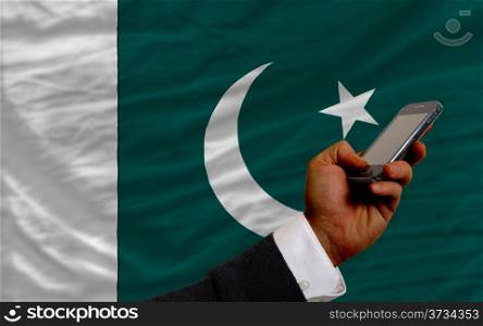 man holding cell phone in front national flag of pakistan symbolizing mobile communication and telecommunication
