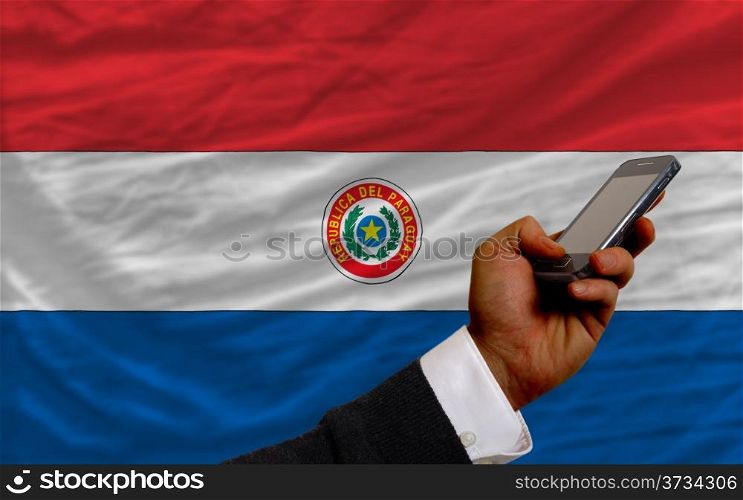 man holding cell phone in front national flag of paraguay symbolizing mobile communication and telecommunication