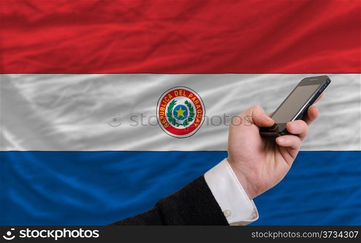 man holding cell phone in front national flag of paraguay symbolizing mobile communication and telecommunication