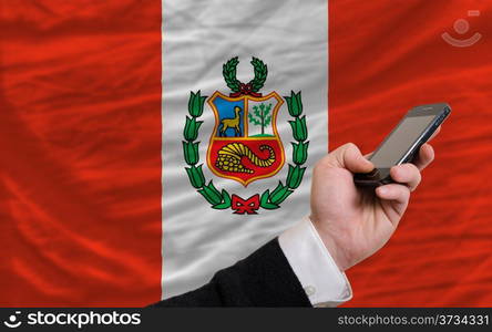 man holding cell phone in front national flag of peru symbolizing mobile communication and telecommunication