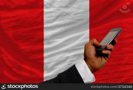 man holding cell phone in front national flag of peru symbolizing mobile communication and telecommunication