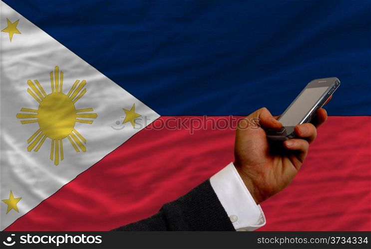 man holding cell phone in front national flag of philippines symbolizing mobile communication and telecommunication