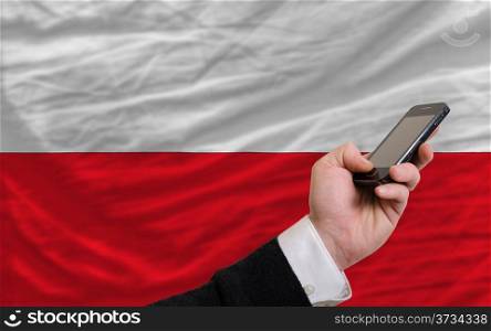 man holding cell phone in front national flag of poland symbolizing mobile communication and telecommunication