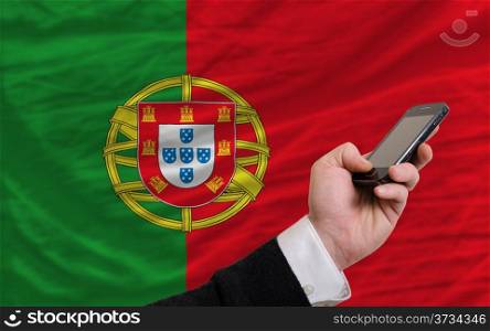 man holding cell phone in front national flag of portugal symbolizing mobile communication and telecommunication
