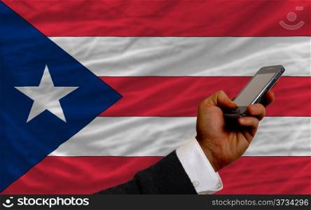 man holding cell phone in front national flag of puertorico symbolizing mobile communication and telecommunication