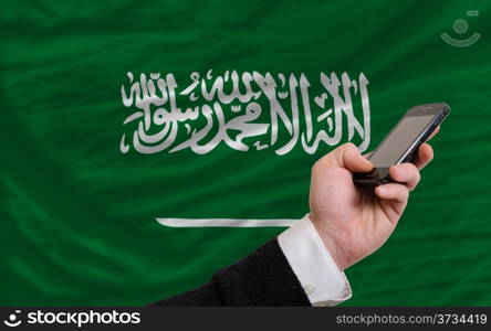 man holding cell phone in front national flag of saudi arabia symbolizing mobile communication and telecommunication