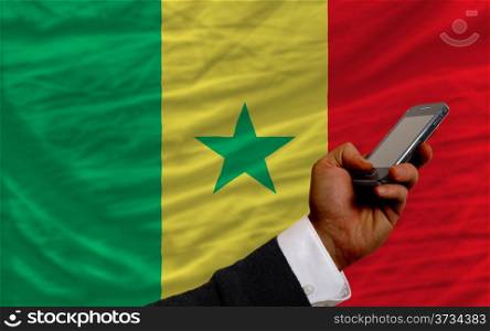 man holding cell phone in front national flag of senegal symbolizing mobile communication and telecommunication