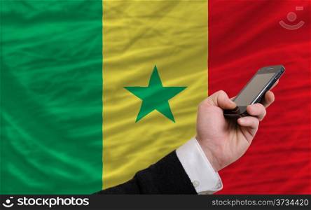 man holding cell phone in front national flag of senegal symbolizing mobile communication and telecommunication