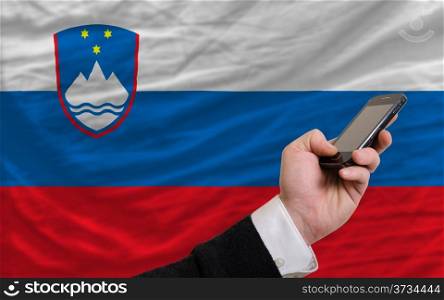 man holding cell phone in front national flag of slovenia symbolizing mobile communication and telecommunication