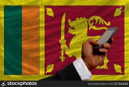 man holding cell phone in front national flag of srilanka symbolizing mobile communication and telecommunication