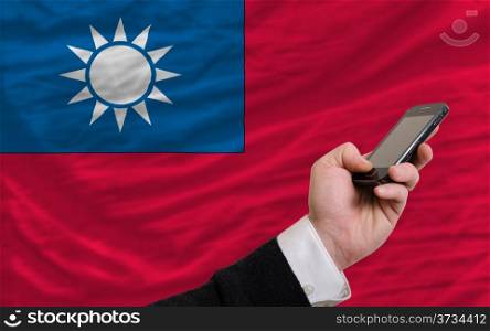 man holding cell phone in front national flag of taiwan symbolizing mobile communication and telecommunication