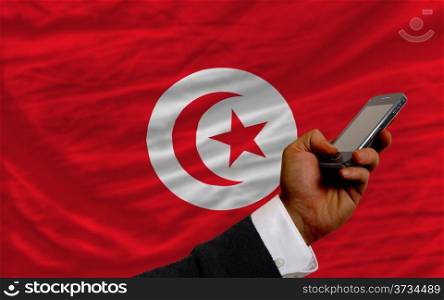 man holding cell phone in front national flag of tunisia symbolizing mobile communication and telecommunication