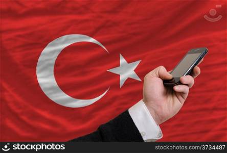 man holding cell phone in front national flag of turkey symbolizing mobile communication and telecommunication