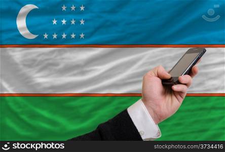 man holding cell phone in front national flag of uzbekistan symbolizing mobile communication and telecommunication