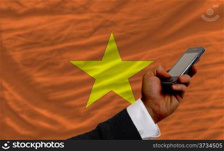 man holding cell phone in front national flag of vietnam symbolizing mobile communication and telecommunication