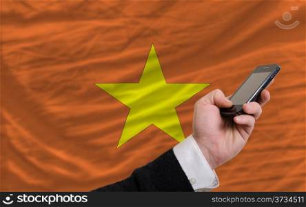 man holding cell phone in front national flag of vietnam symbolizing mobile communication and telecommunication