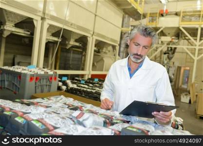 Man holding clipboard checking packaged goods