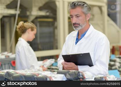 Man holding clipboard looking at plastic packages