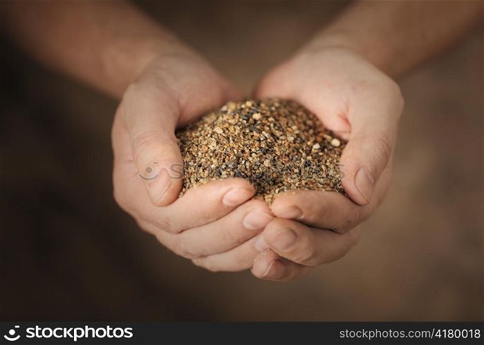 Man holding coarse sand in his cupped hands.