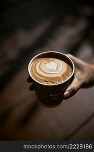 Man holding coffee cup with latte art, Selective focus. Man holding coffee cup with latte art
