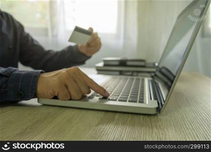 Man holding credit card and using laptop for payment shopping online.