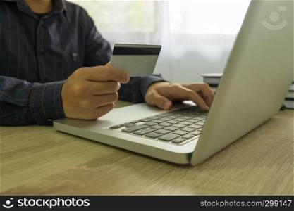 Man holding credit card and using laptop for payment shopping online.