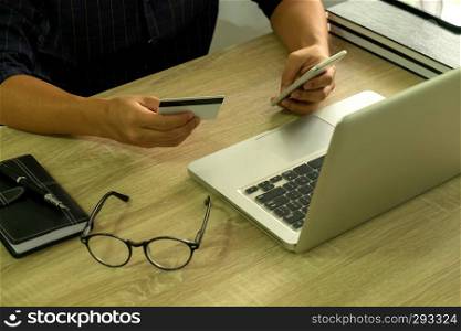 Man holding credit card and using smartphone for payment shopping online.