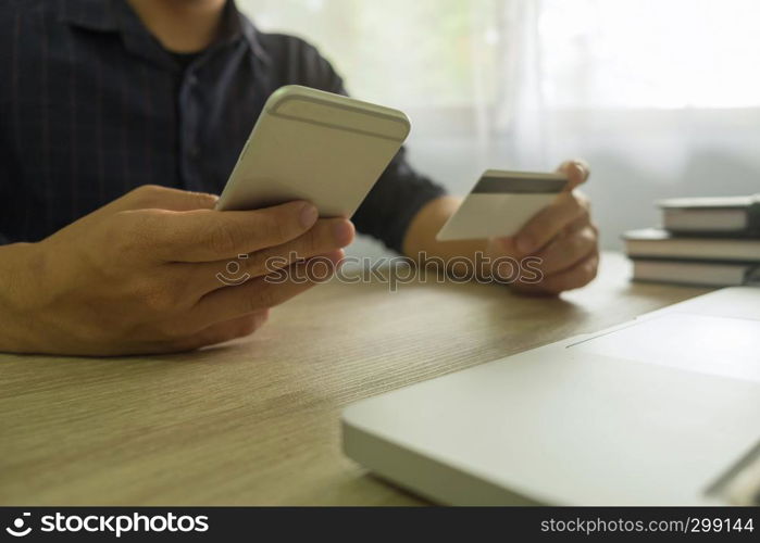 Man holding credit card and using smartphone for payment shopping online.